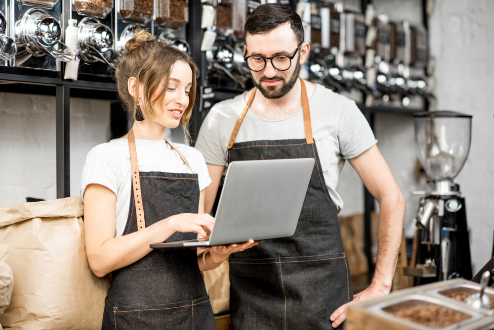 twee werknemers achter een laptop in een koffiezaak