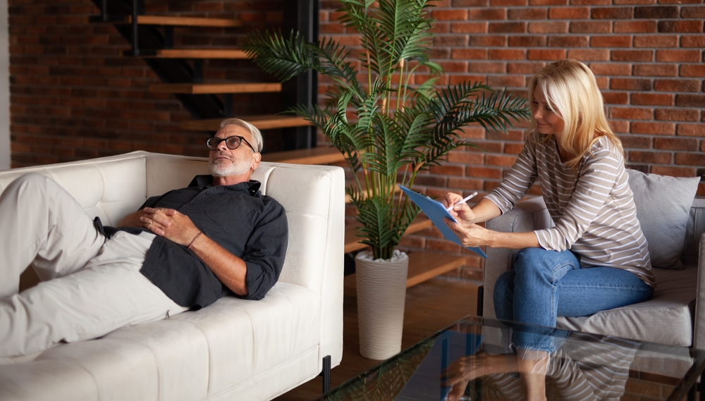 man met baard ligt in zetel bij psycholoog